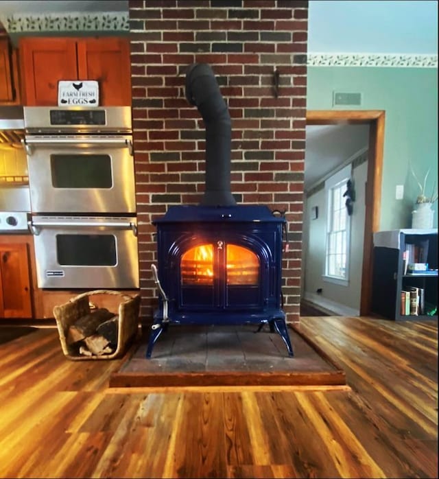 details featuring double oven, dark wood-type flooring, wood counters, and a wood stove