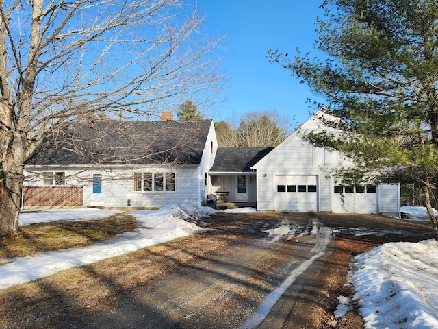 view of front of house featuring a garage, a chimney, driveway, and a shingled roof