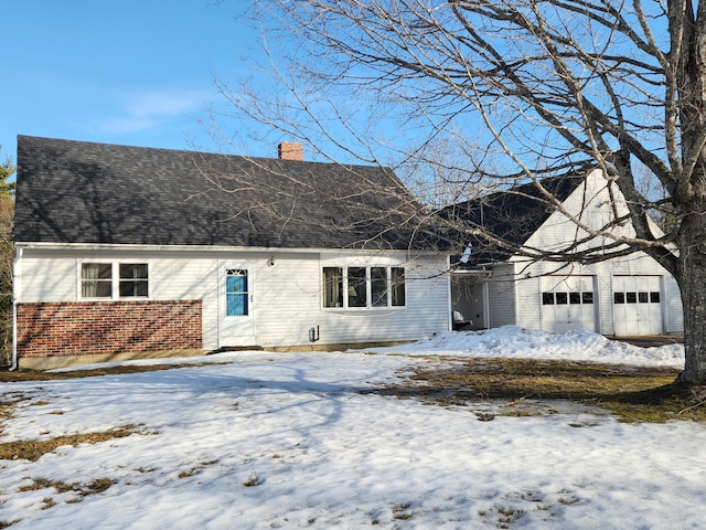 view of front of house with a shingled roof, brick siding, a garage, and a chimney