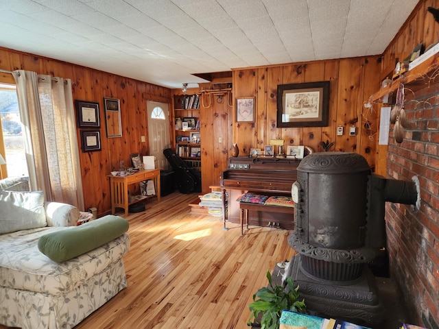 living area with wood walls, a wood stove, and light wood finished floors