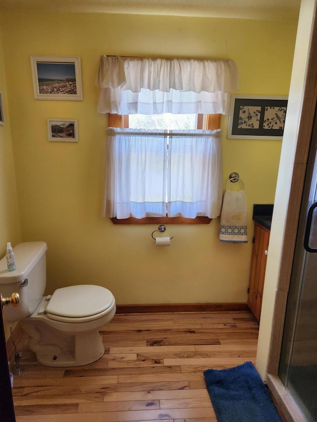 full bathroom with a stall shower, toilet, wood finished floors, and vanity