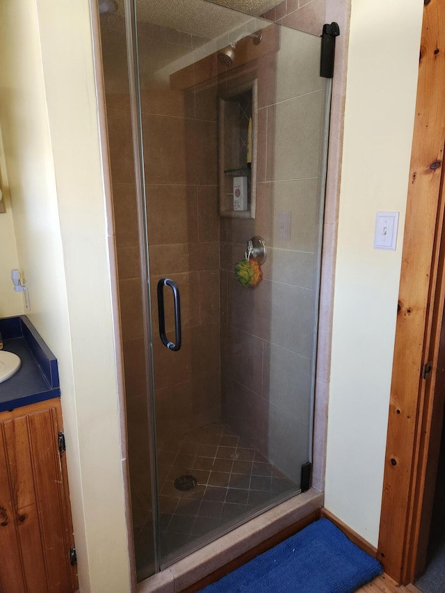 full bathroom with baseboards, a stall shower, and vanity