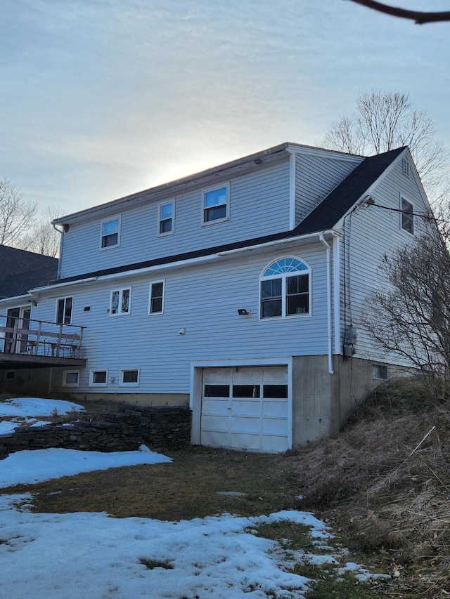 snow covered property with an attached garage