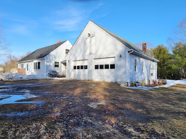 view of home's exterior with driveway, an outdoor structure, and a chimney