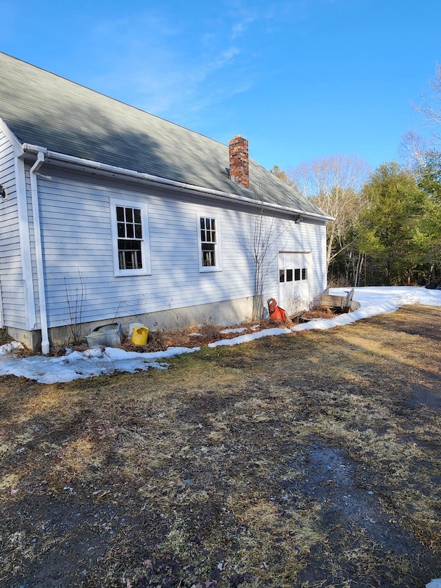 view of property exterior featuring an attached garage and a chimney