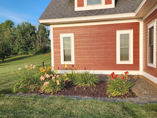 view of property exterior featuring a shingled roof and a lawn