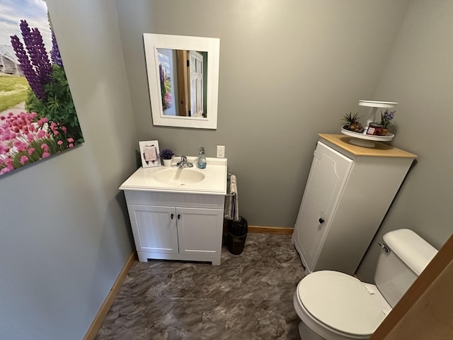 half bath featuring baseboards, vanity, and toilet