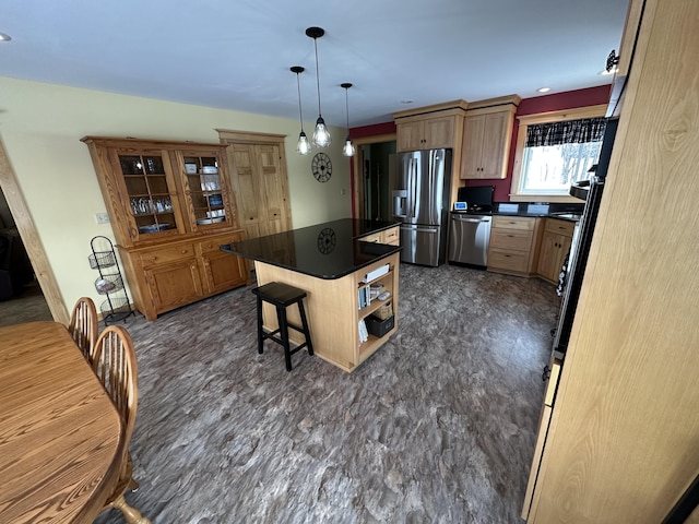 kitchen featuring a breakfast bar, stainless steel appliances, dark countertops, hanging light fixtures, and a kitchen island