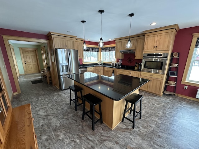 kitchen featuring appliances with stainless steel finishes, a breakfast bar area, dark countertops, and pendant lighting