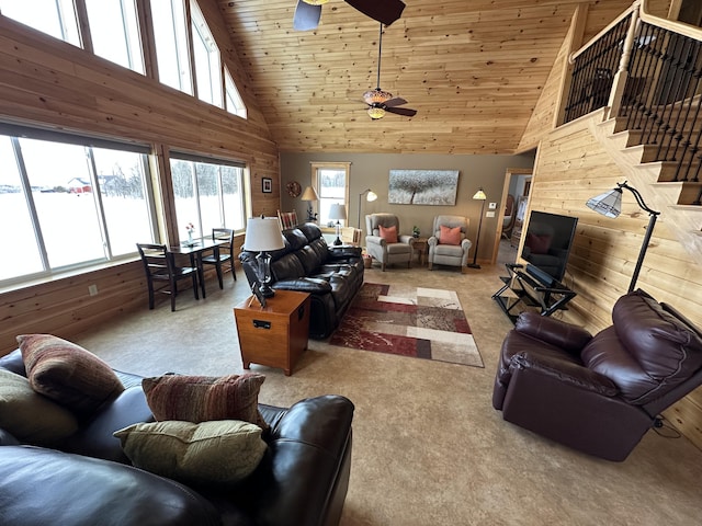 living area with wooden ceiling, wood walls, ceiling fan, and stairway