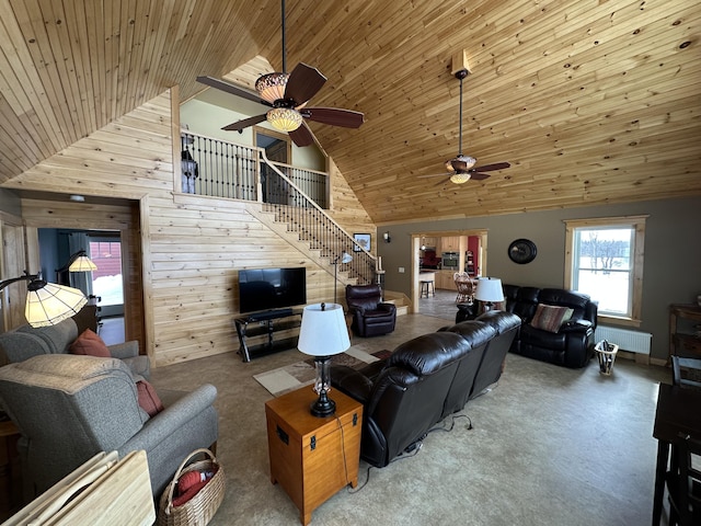 carpeted living room with radiator, stairway, wooden walls, high vaulted ceiling, and wooden ceiling