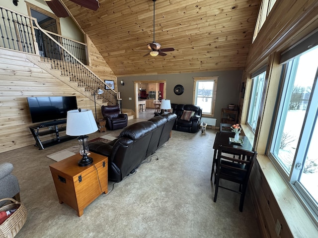 living room featuring stairway, a ceiling fan, wood walls, high vaulted ceiling, and wooden ceiling