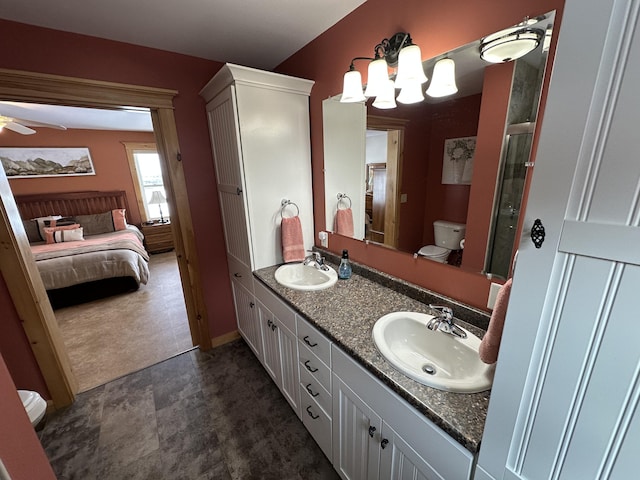 ensuite bathroom with toilet, double vanity, a sink, and a shower with shower door