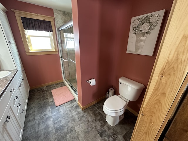 bathroom featuring a stall shower, baseboards, vanity, and toilet