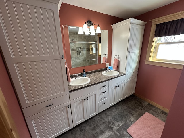 full bath featuring a sink, a shower stall, baseboards, and double vanity