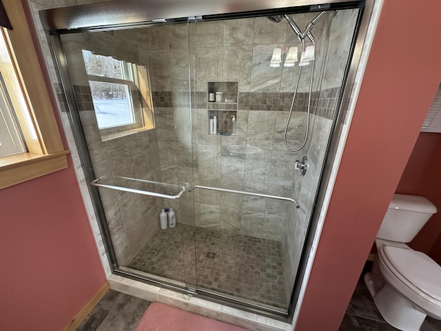 bathroom with tile patterned flooring, baseboards, a shower stall, and toilet