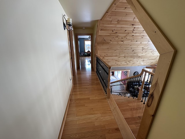 hall featuring light wood finished floors, an upstairs landing, and baseboards