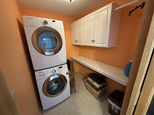 washroom featuring cabinet space, light tile patterned floors, and stacked washer / dryer