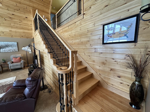 stairway featuring a high ceiling, wood walls, and wood finished floors