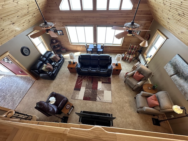 unfurnished living room featuring high vaulted ceiling, a ceiling fan, and wooden walls