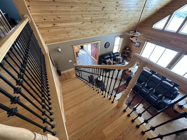 staircase with high vaulted ceiling, wooden ceiling, baseboards, and wood finished floors