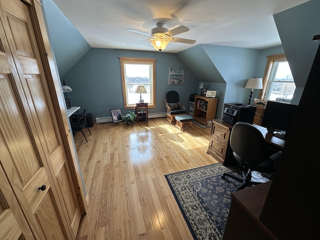 home office with light wood-style floors, a healthy amount of sunlight, and vaulted ceiling