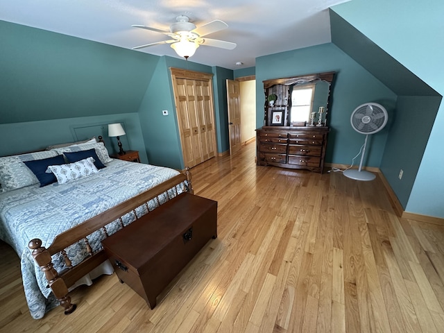 bedroom with a closet, light wood-style flooring, vaulted ceiling, ceiling fan, and baseboards