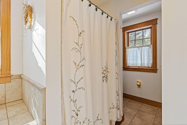 bathroom with a shower with shower curtain, tile patterned flooring, and baseboards