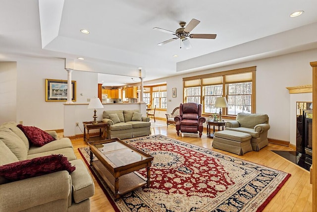 living area featuring light wood finished floors, a fireplace, baseboards, and recessed lighting