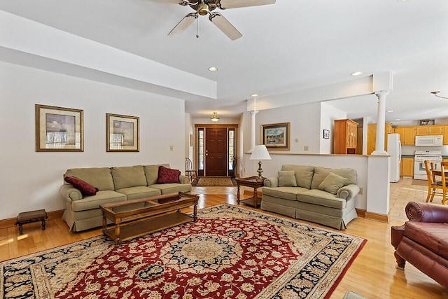 living area with ceiling fan, light wood-style floors, baseboards, and ornate columns