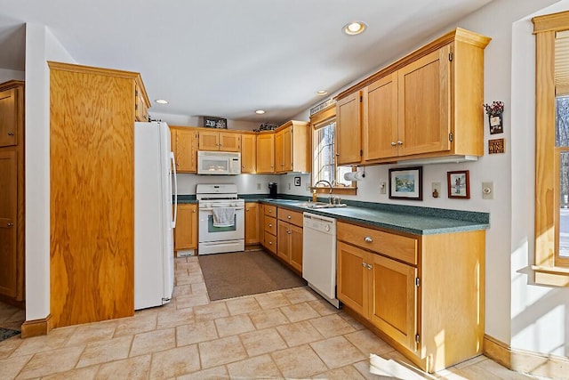 kitchen featuring white appliances, dark countertops, stone finish flooring, a sink, and recessed lighting