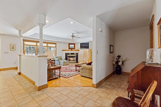 living area with decorative columns, recessed lighting, a glass covered fireplace, ceiling fan, and baseboards