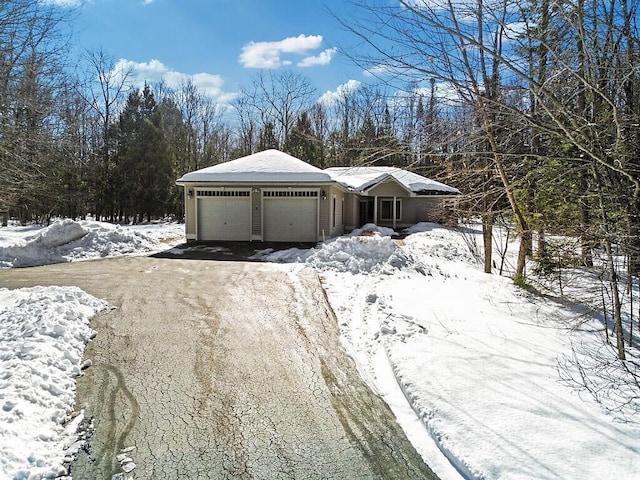 snow covered garage featuring driveway