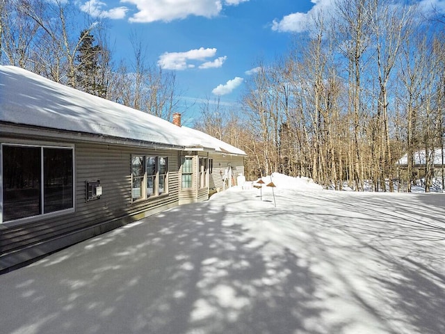 snow covered property with a chimney