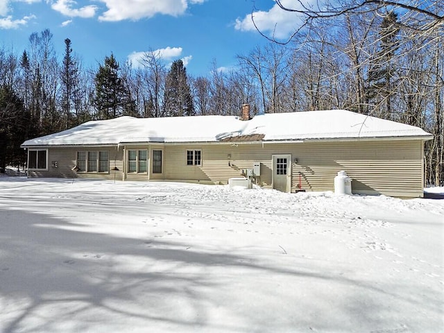 snow covered property with a chimney and cooling unit