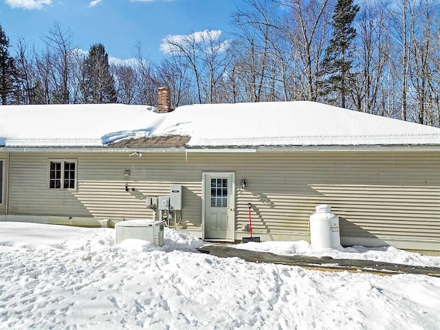 snow covered house featuring a chimney