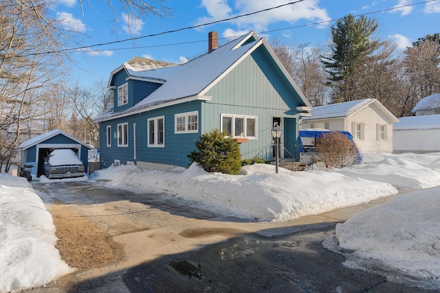 view of snow covered exterior featuring an outbuilding and a chimney