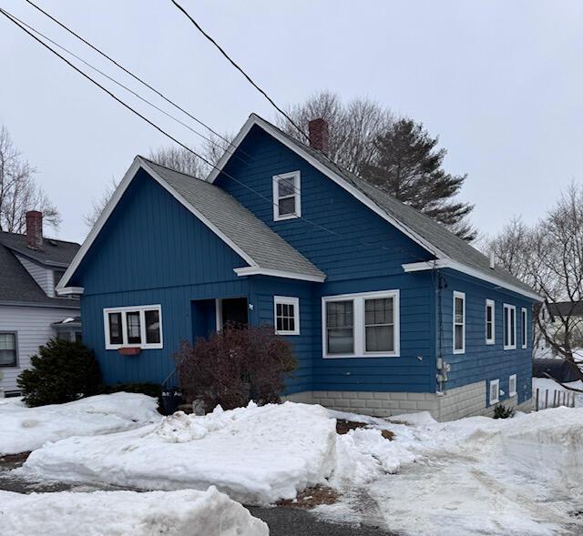 view of front of house with a shingled roof and a chimney