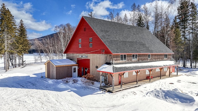 view of front of home featuring a garage, roof with shingles, an outdoor structure, and a barn