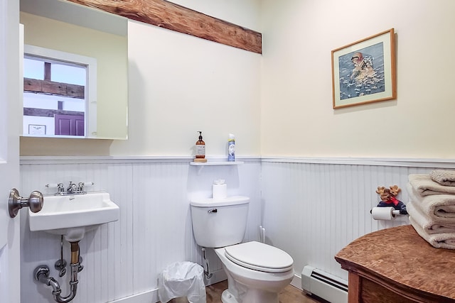 half bath featuring toilet, baseboard heating, and wainscoting