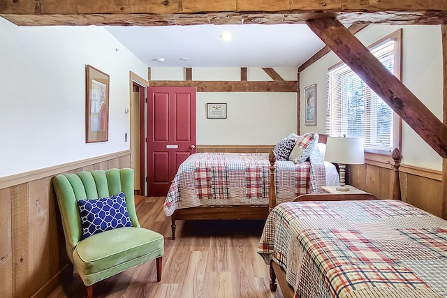 bedroom with wood walls, wainscoting, and light wood-style floors