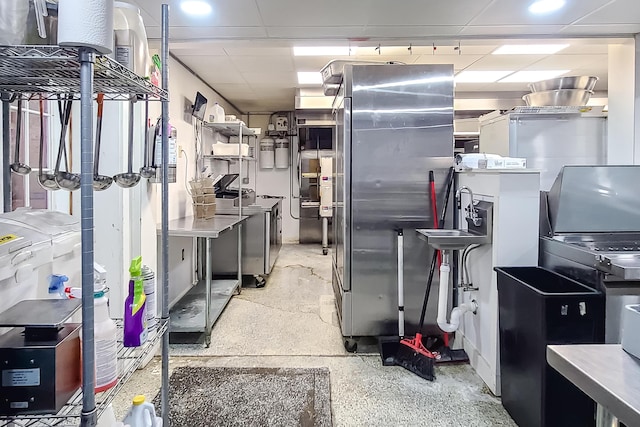 kitchen with light speckled floor, freestanding refrigerator, a paneled ceiling, and washer / dryer