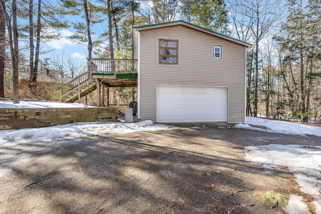 view of snowy exterior featuring a garage, a deck, and stairs