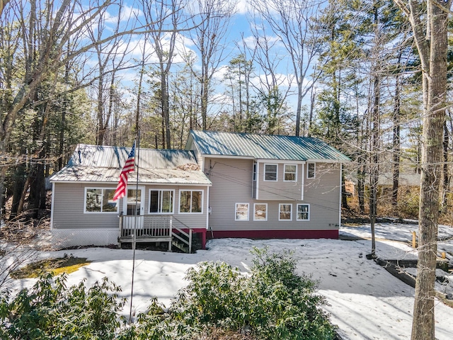 snow covered house featuring metal roof