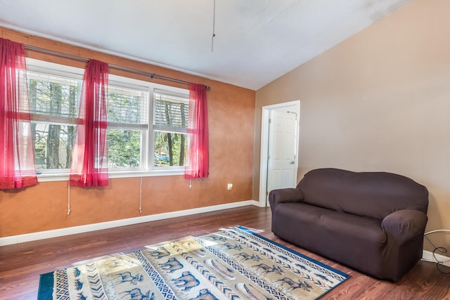 living area featuring vaulted ceiling, wood finished floors, and baseboards