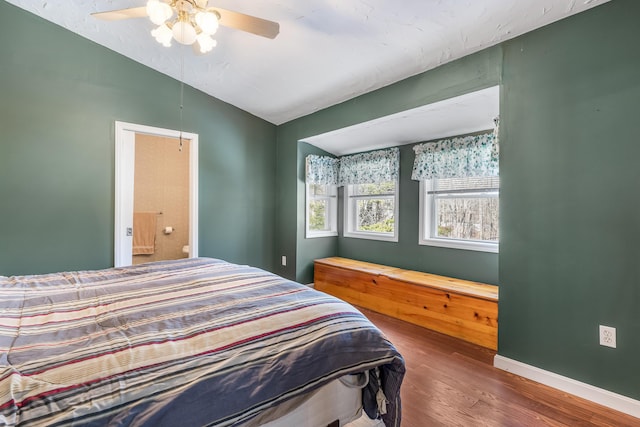 bedroom with connected bathroom, ceiling fan, baseboards, lofted ceiling, and wood finished floors