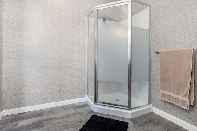 bathroom featuring baseboards, wood finished floors, and a shower stall