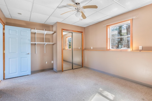 unfurnished bedroom featuring a closet, multiple windows, baseboards, and a drop ceiling