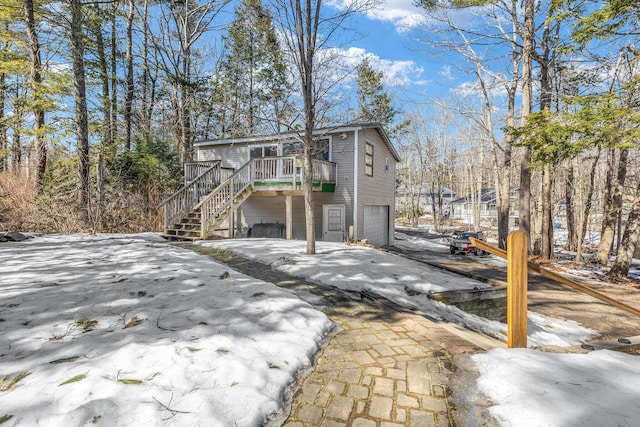 rear view of property featuring an attached garage, a wooden deck, and stairs