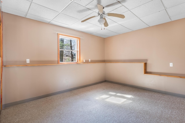 unfurnished room featuring ceiling fan, baseboards, a drop ceiling, and carpet floors